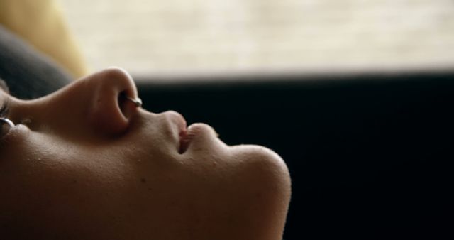 Close-up of a contemplative person lying on couch, revealing serene moment. Useful for themes of relaxation, introspection, and peacefulness. Suitable for wellness, mental health, and lifestyle content.