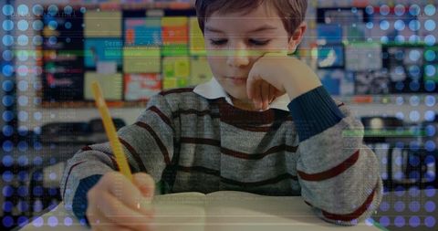 Boy coding in classroom with pencil and notebook