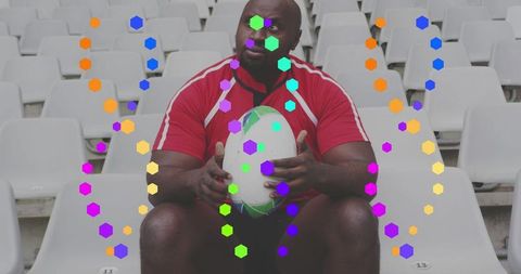 Sitting black rugby player holding ball in stadium seats with vibrant hexagon overlay