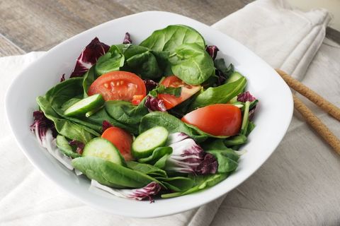 Fresh spinach and radicchio salad with tomato and cucumber in white bowl for healthy menu