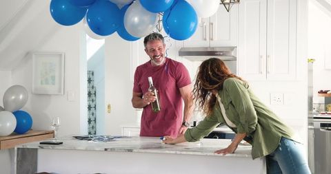 Couple Tidying Kitchen After Birthday Celebration With Blue Balloons