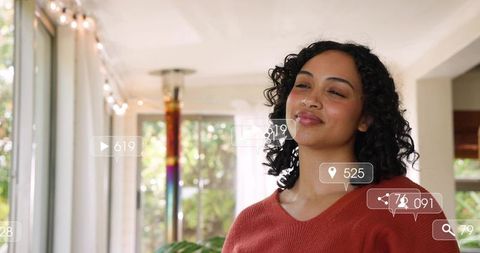 Confident woman by glass doors with social media overlays, cozy home portrait