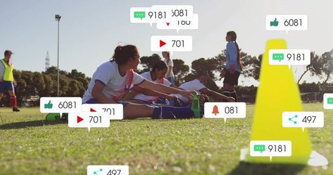 Women soccer team stretching on field with social media notifications rising during training