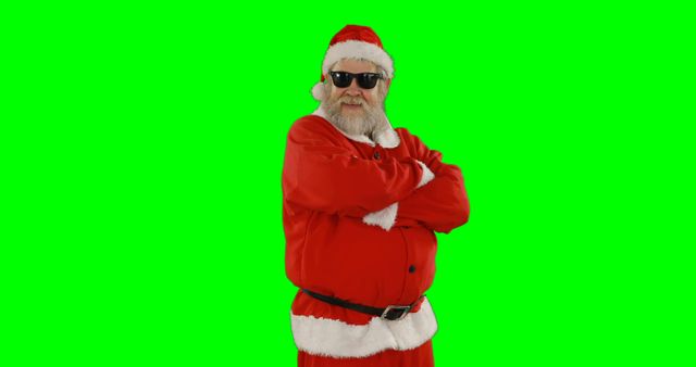 Santa Claus dressed in traditional red costume, wearing sunglasses, stands with arms crossed against a green screen background. Perfect for holiday-themed marketing, greeting cards, festive promotions, or any creative project requiring a holiday character with a cool twist and the adaptability of a green screen background.