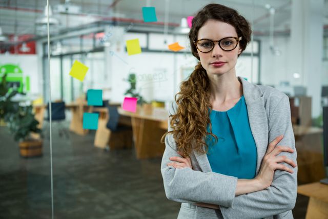 Portrait of confident female executive standing with arms crossed in creative office