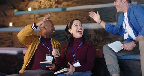 Multicultural team laughing, high-fiving and taking notes during interactive workshop