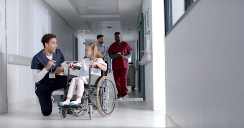 Young Nurse Assisting Child in Wheelchair in Hospital Corridor