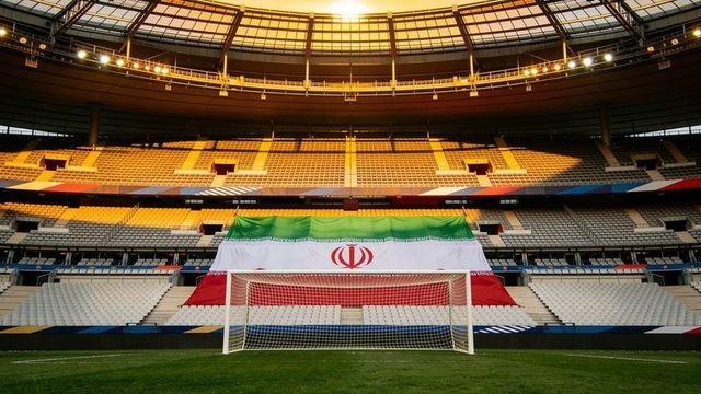 Empty stadium featuring soccer goal and giant iranian flag at golden sunset