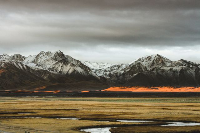 Snow-Capped Mountains with Dramatic Lighting and Foreground Fields - Download Free Stock Photos Pikwizard.com