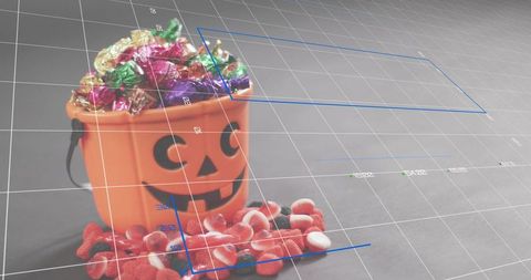 Overflowing halloween jack-o'-lantern candy bucket with wrapped sweets and gummy spill