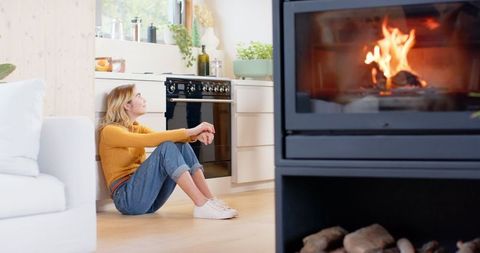 Woman Relaxing in Modern Kitchen Near Cozy Fireplace