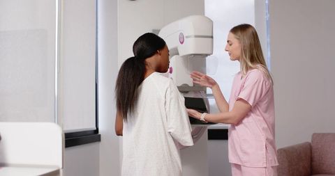 Radiology technologist guiding patient for mammogram positioning during breast screening
