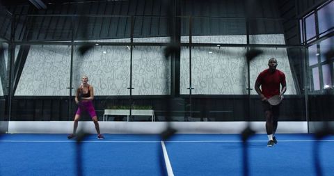 Athletes playing paddle on modern blue court with urban mural