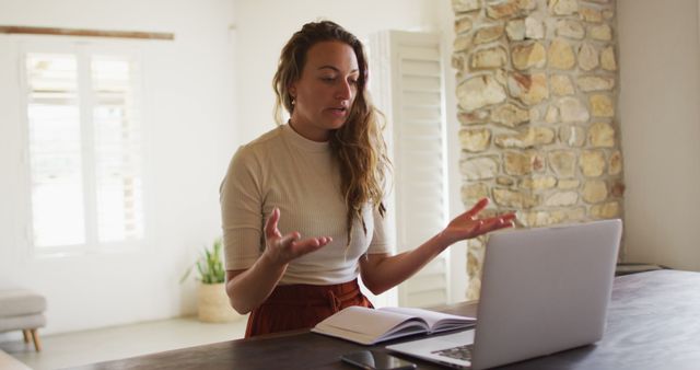 Smiling caucasian woman working from home making image call using laptop, talking and gesturing. working at home in isolation during quarantine lockdown.