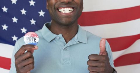 Smiling voter holding badge against american flag background