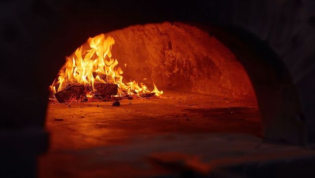 Rustic wood-fired oven with burning logs and spiraling flames