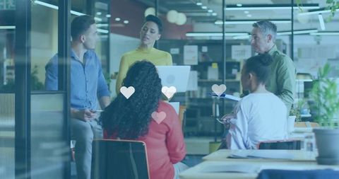 Presenting woman leading diverse team meeting in modern glass office with heart icons