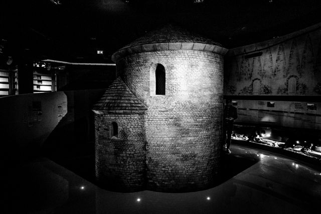 Showcasing old medieval stone roundhouse in atmospheric dark museum exhibit. Perfect for use in history articles, educational materials on medieval architecture, cultural heritage exhibitions, museum brochures, and historical documentaries.