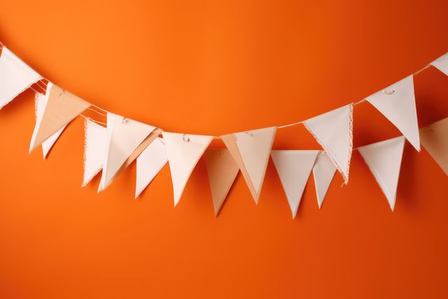 Triangular white bunting garland hanging against a vibrant orange background, creating a festive and cheerful atmosphere. Perfect for use in party invitations, celebration promotions, event planning materials, and decorative purposes.