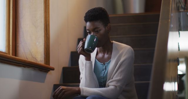 Thoughtful african american attractive woman sitting on stairs an, drinking coffee - Download Free Stock Photos Pikwizard.com
