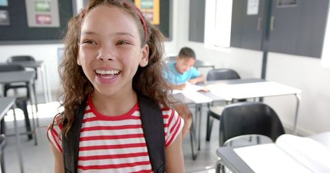 Joyful student with backpack in classroom