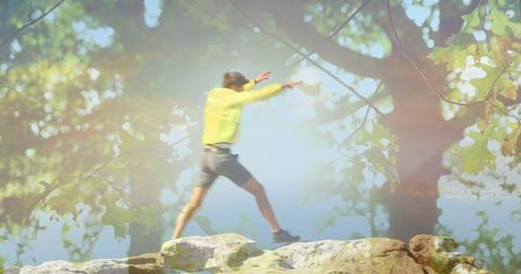 Man Jumping on Mountain Rocks with Triumphant Gesture