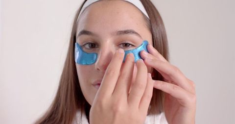 Woman applying under-eye gel patches for skincare