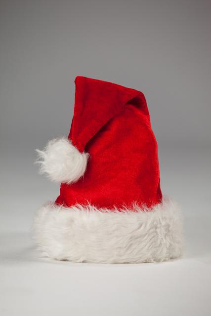 This close-up shot of a red Santa hat with a white fur trim is perfect for festive holiday themes. Use it for Christmas advertising, holiday greeting cards, or seasonal decoration ideas.