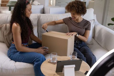 African american friends unboxing delivery parcel together on cozy living room sofa