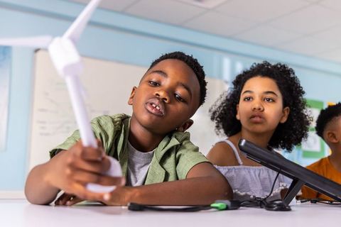 Students exploring model wind turbine in stem classroom collaboration and hands-on learning