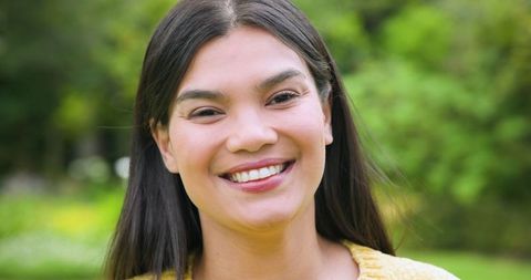 Smiling Young Woman Wearing Yellow Knit Sweater in Park