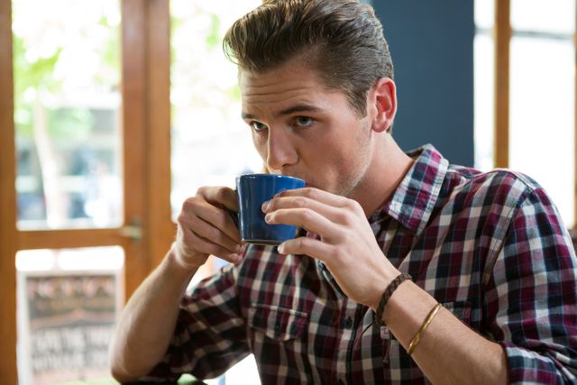 Handsome young man drinking coffee in cafeteria
