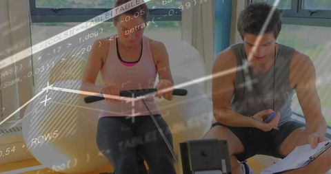 Indoor rowing training session with female athlete and coach tracking performance data