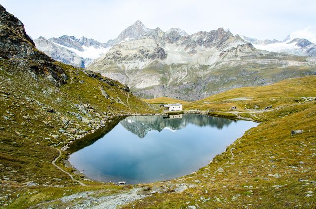 This tranquil scene of a mountain lake with clear reflections of alpine peaks offers a sense of peace and serenity. Surrounded by rocky terrain, it is ideal for use in nature magazines, travel brochures, or websites promoting outdoor adventures. The serene landscape captures the essence of natural beauty, making it perfect for background use in presentations or wallpapers.