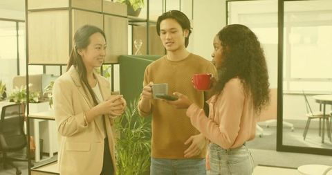 Colleagues engaging in coffee break discussion in modern office