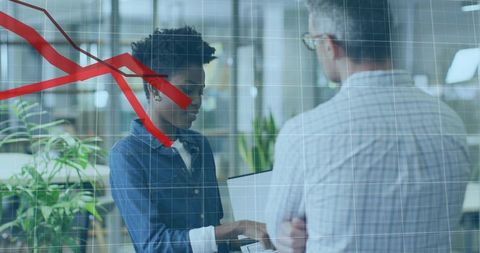 Colleagues collaborating over laptop with red graph overlay showing business decline