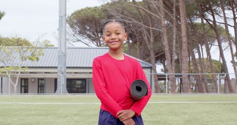 Young Boy Holding Exercise Mat on Outdoor Sports Field
