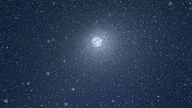 Full moon radiating soft halo through falling snow in starry night sky