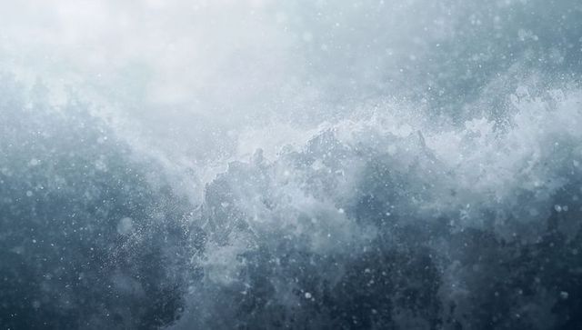 Crashing ocean wave sending foamy crest and dense spray during stormy sea closeup