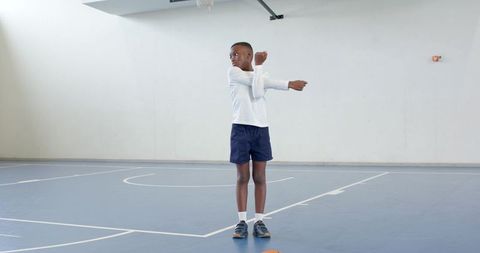 Boy stretching on indoor basketball court emphasizing fitness and preparation