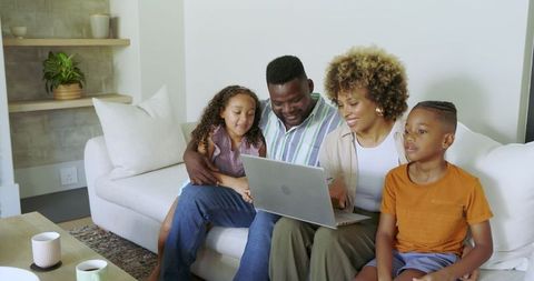 Happy Family Smiling Together While Browsing Laptop at Home