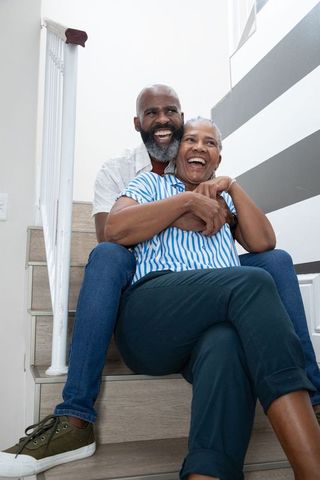 Senior Couple Embracing on Staircase Laughing Happily at Home