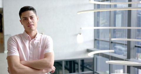 Confident young professional in modern office with crossed arms