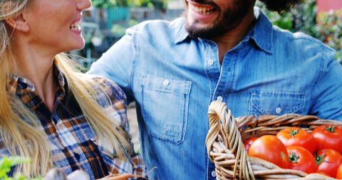Happy Gardeners Holding Freshly Harvested Vegetables in Garden