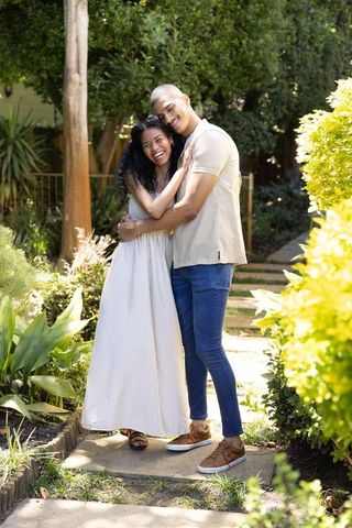 African american couple embracing on garden pathway smiling in sunny outdoor romance