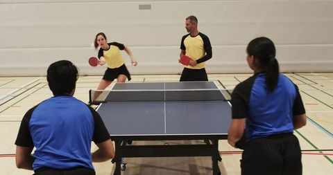 Intense Doubles Table Tennis Match in Gym