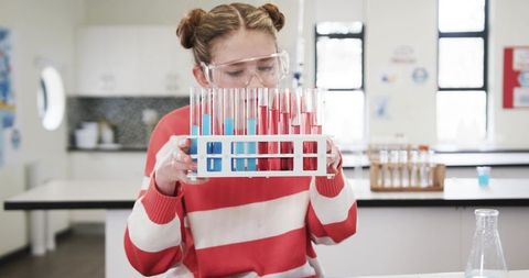 Young Girl in School Laboratory Holding Test Tubes, Engaged in Science Experiment