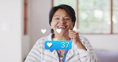 Smiling senior indian woman celebrating social media likes with blue 37 engagement bubble