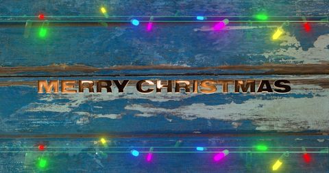 Merry Christmas Text on Rustic Blue Wooden Background with Lights