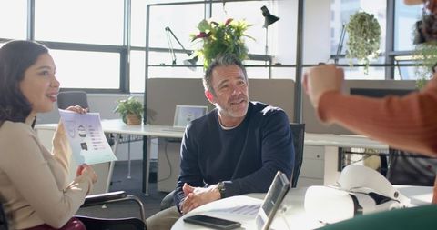 Multicultural team collaborating around round table in modern open-plan office with tablet and chart